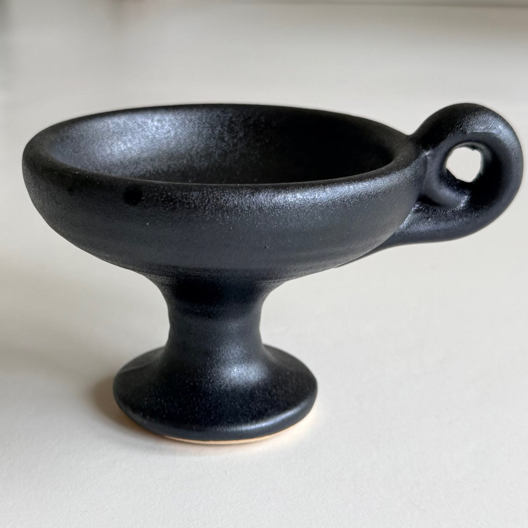 Close-up of a black ceramic incense burner and its round ring handle.