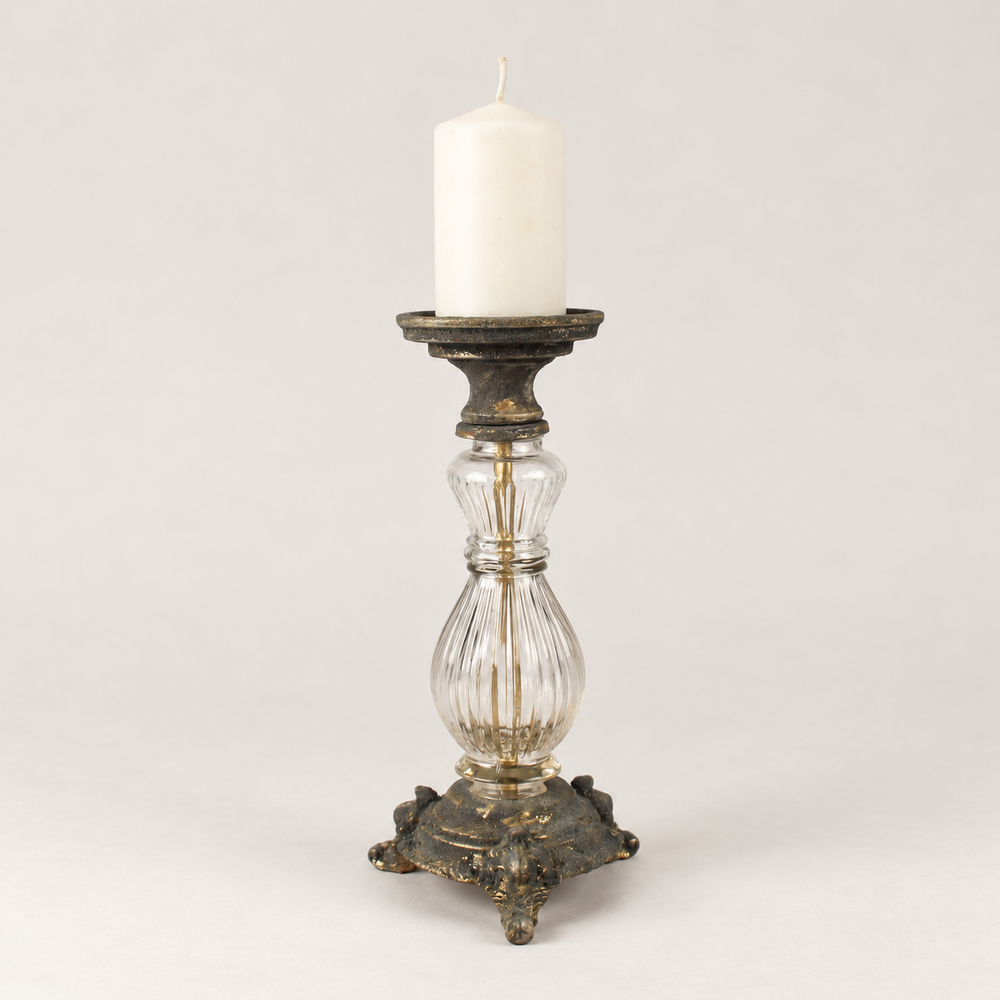 Lasinen ja metallinen antiikkityylinen kynttilänjalka kuvattuna valkoisen pöytäkynttilän kanssa. Kynttilä ei sisälly tuotteeseen. / Antique-style glass and metal candle holder shown with a white pillar candle. Candle not included.
