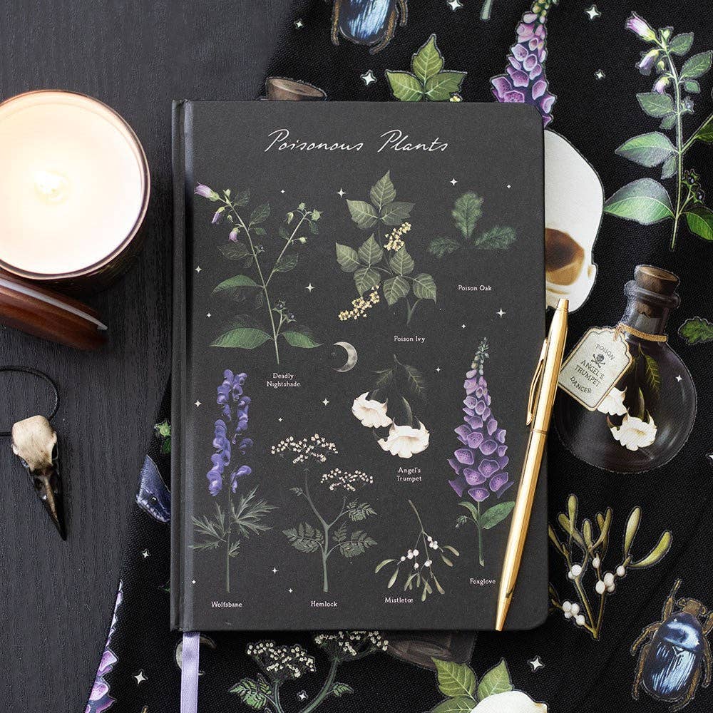 Poisonous Plants -muistikirja kasvikuvioisen kankaan päällä kynän ja kynttilän vieressä.