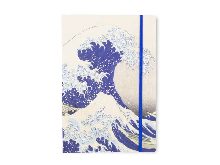 Hokusain Suuri aalto -muistikirjan etukansi, sinivalkoinen aaltokuvitus ja sininen kuminauha. – Front cover of the Hokusai Great Wave notebook with a blue-and-white wave illustration and blue elastic closure.