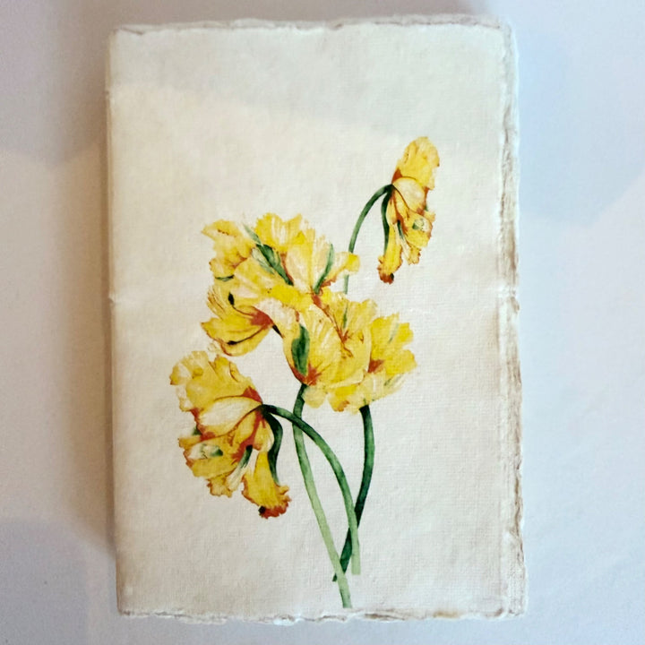 Vaalea käsintehty muistikirja, kuva-aiheena keltaiset tulppaanit. / Cream handmade notebook with yellow tulips on the cover.