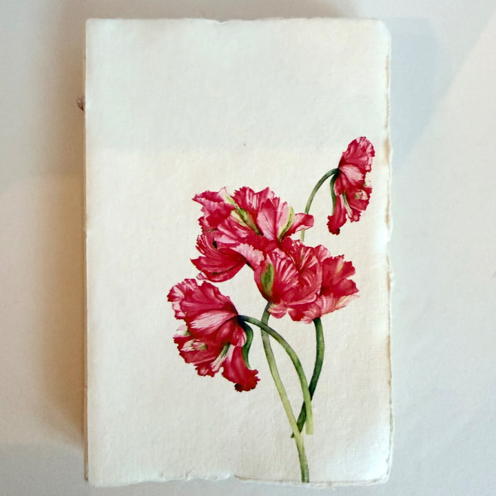 Vaalea käsintehty muistikirja, kuva-aiheena punaiset tulppaanit. / Cream handmade notebook with red tulips on the cover.