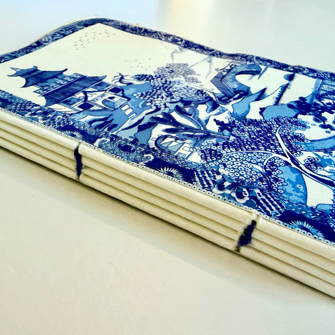Puutarha-aiheisen muistikirjan lankasidonta ja puuvillapaperisivut sivulta kuvattuina. / Side view of the garden notebook showing its sewn binding and cotton paper pages.