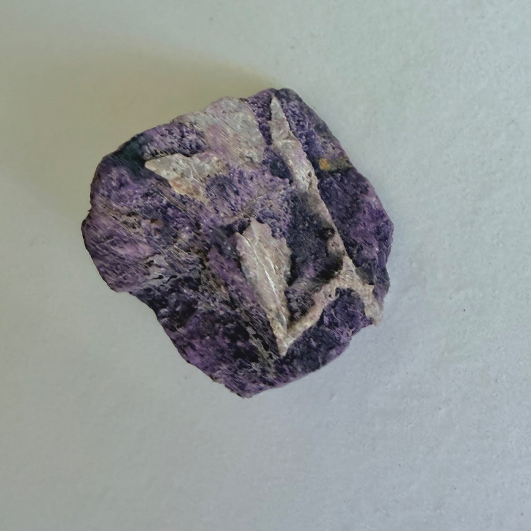Purpurite Stone 1, an elongated violet rough mineral with pale mineral areas.
