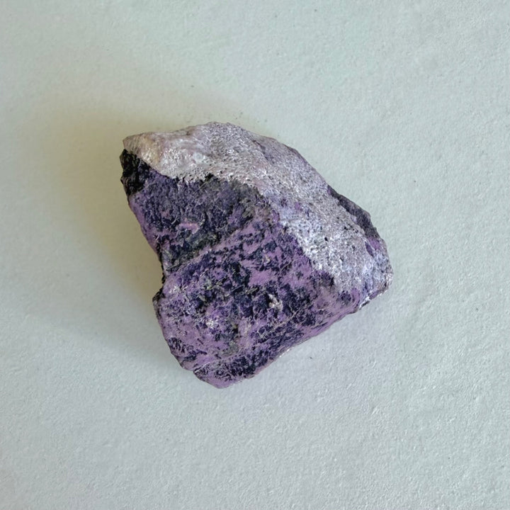 Purpurite Stone 2 viewed from the side, showing dark and pale mineral areas.