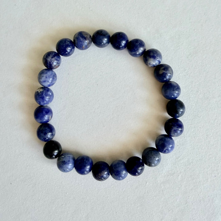 Sodalite bracelet with polished blue 8 mm beads, photographed from above on a pale background.