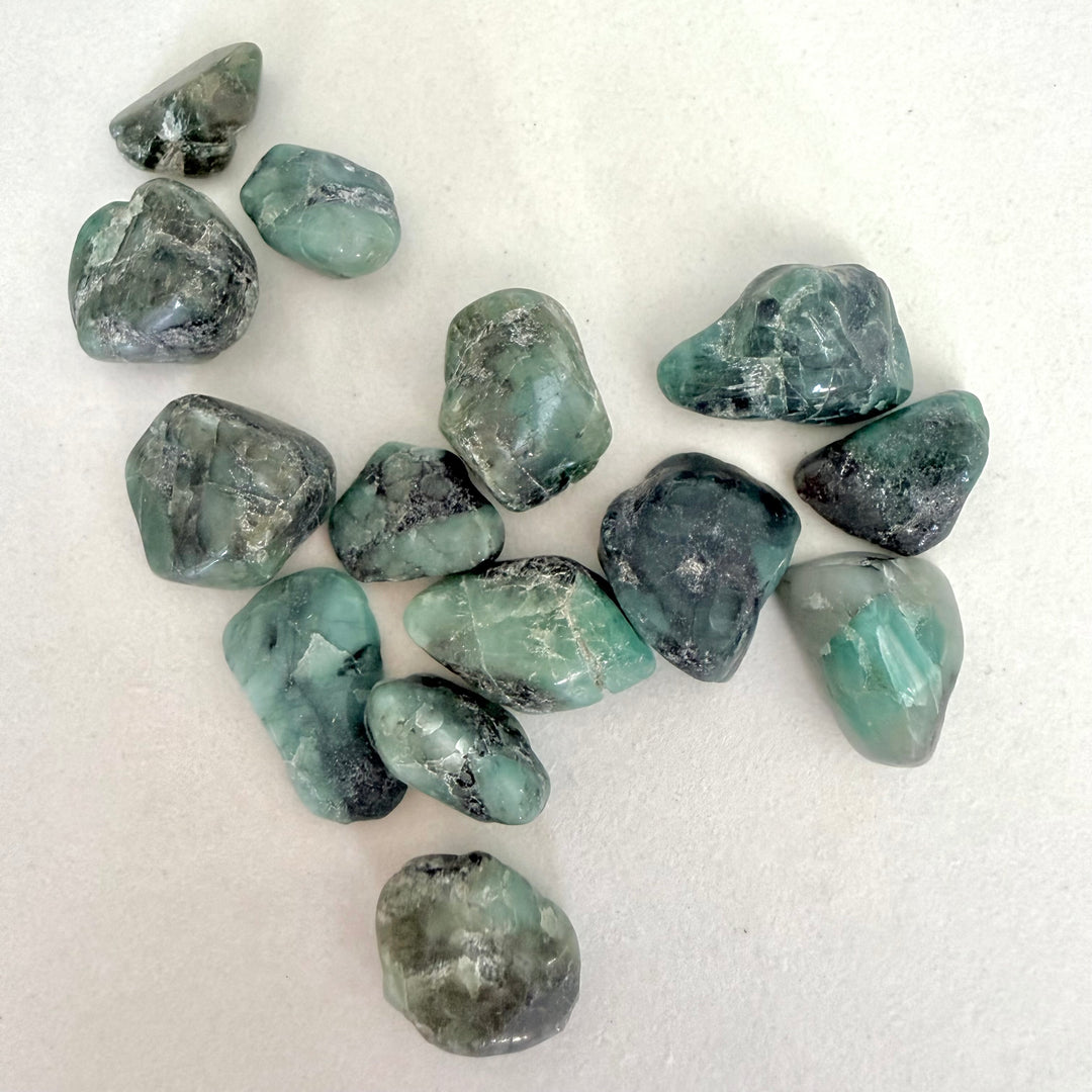 Rumpuhiottuja vihreitä smaragdikiviä valkoisella taustalla.