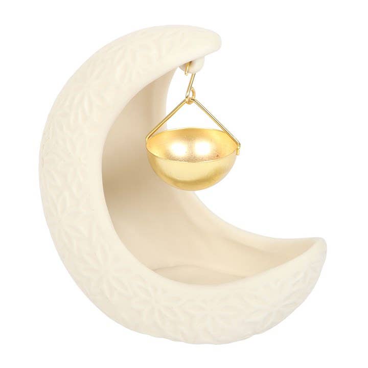 White ceramic crescent moon oil burner with a suspended gold-coloured bowl against a pale background.