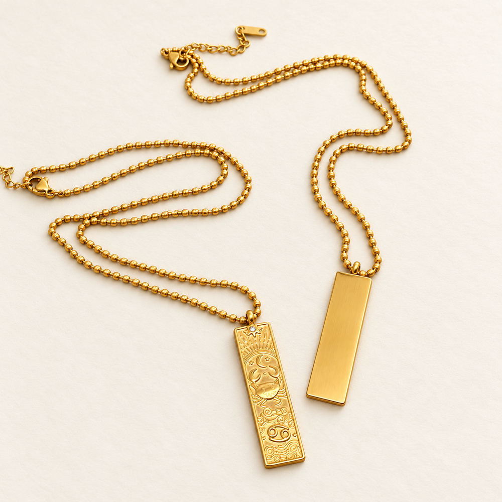 The decorated front and smooth reverse of the 18K gold-plated Cancer Zodiac necklace on a light background.