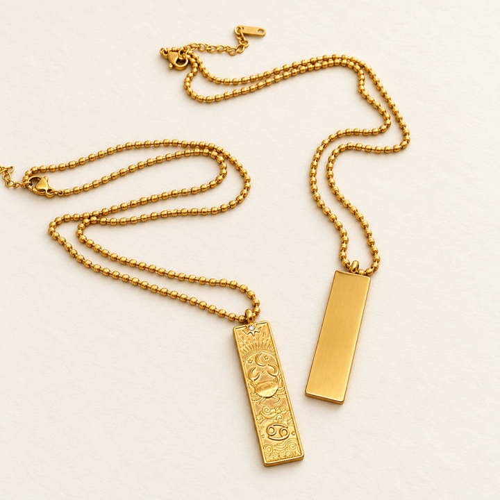 The decorated front and smooth reverse of the 18K gold-plated Cancer Zodiac necklace on a light background.